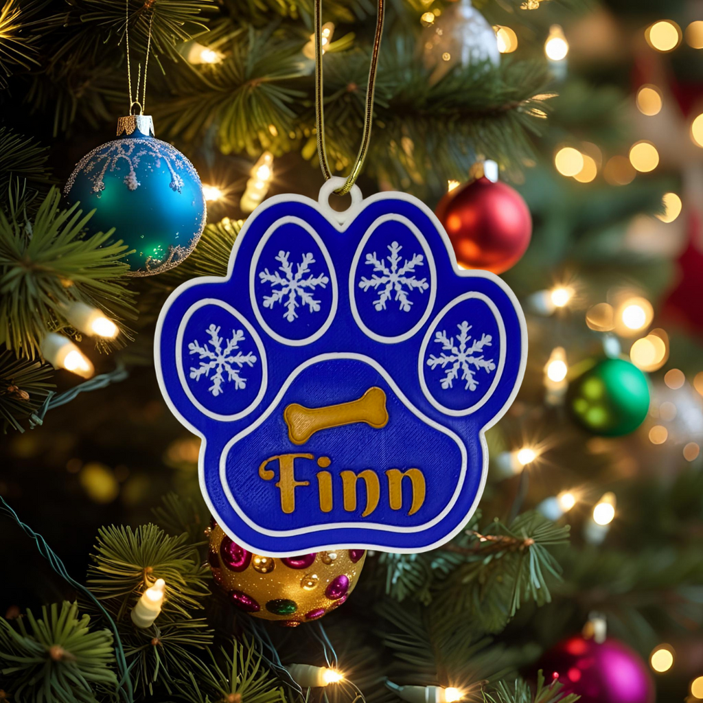 Blue paw print ornament with 'Finn' on a Christmas tree