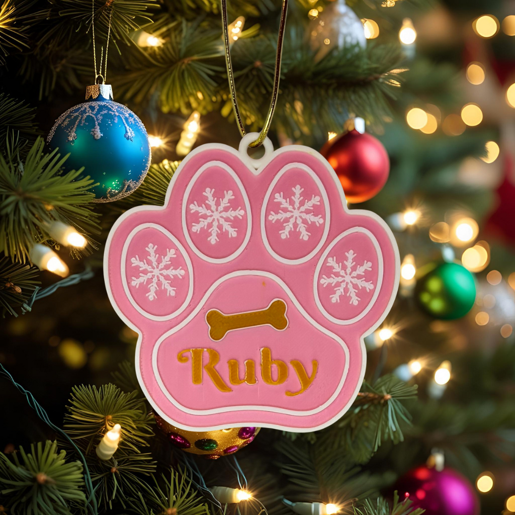 Pink paw-shaped ornament with 'Ruby' on a Christmas tree