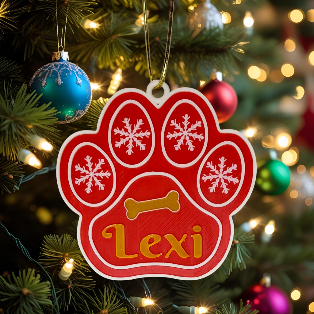 Red paw print ornament with 'Lexi' on a Christmas tree