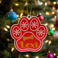Red paw print ornament with 'Lexi' on a Christmas tree